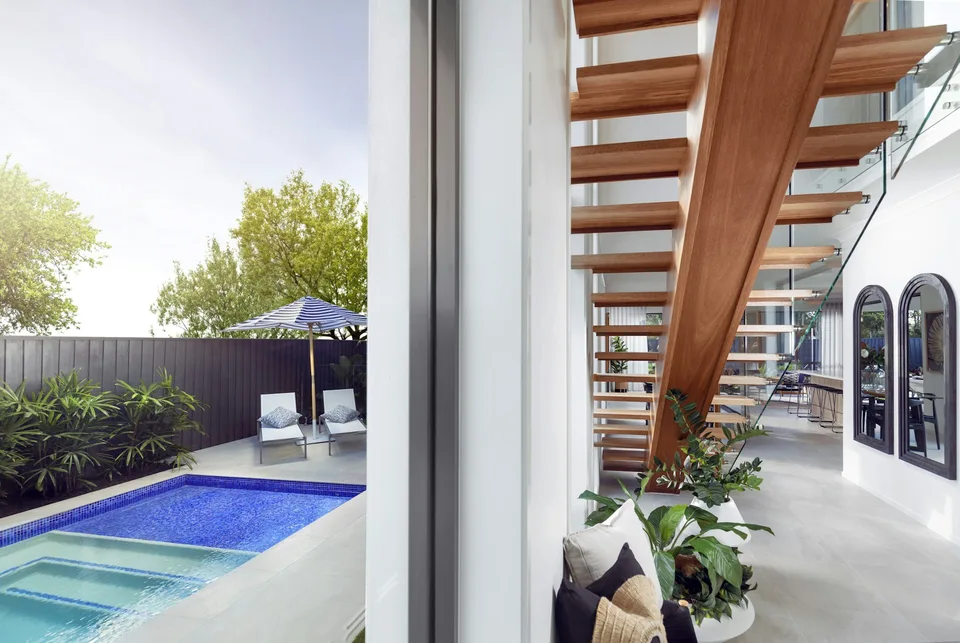 Entry space beneath the staircase opening to the pool through sliding doors.